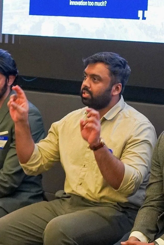 Adnaan speaking on a panel, mid-gesture